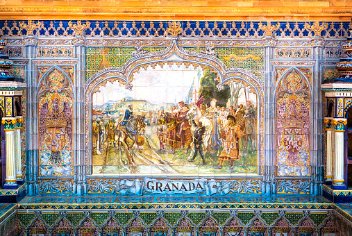 Sevilla, Spain - July 14, 2021: Historic tile bench from the Plaza de Espana in Sevilla, Spain commemorating the reconquest of Granada. The Plaza de Espana was built in 1928 for the Ibero-American Exposition of 1929 and has different cities represented all around the plaza.