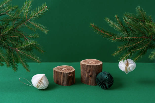 istock Two empty wooden podiums, white paper decorations and fir tree branches on green background. Christmas eco mockup. Natural cosmetic product presentation. Beauty and spa advertising. Wabi sabi concept 1344786666
