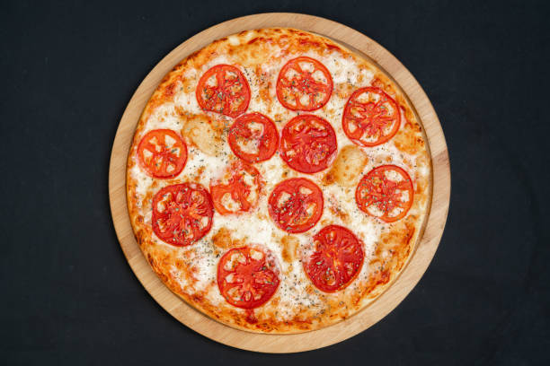 istock Pizza Margherita with Tomatoes on black stone background, top view. 1344790157