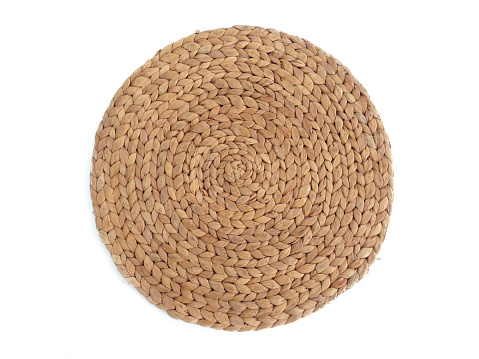 Top view texture of handmade round beige wicker tablecloth surface isolated on white background. Household utensils. Rustic decoration