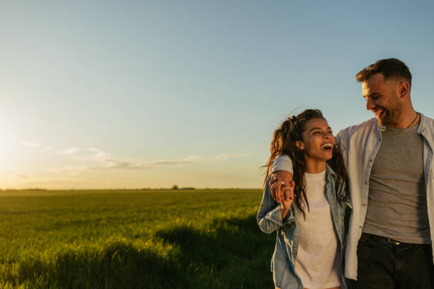 istock Young couple in love walking on pathway through grass field 1344792095