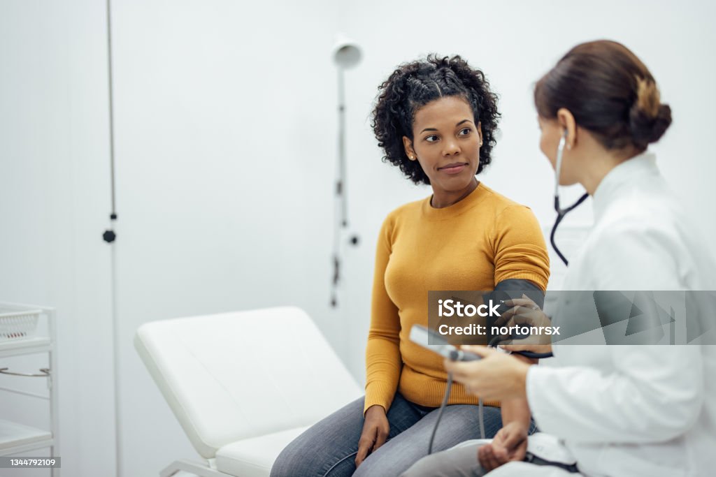 Doctor measuring blood pressure to a smiling woman. Doctor measuring blood pressure to a smiling woman as a part of a medical exam. Medical Exam Stock Photo