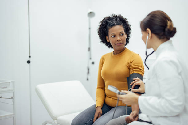 Doctor measuring blood pressure to a smiling woman. Doctor measuring blood pressure to a smiling woman as a part of a medical exam. medical exam stock pictures, royalty-free photos & images