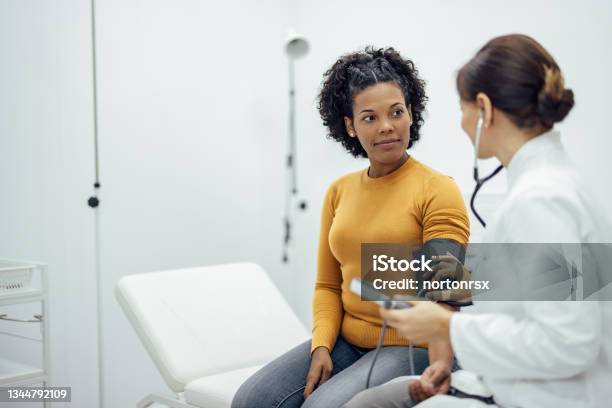 Doctor Measuring Blood Pressure To A Smiling Woman Stock Photo - Download Image Now
