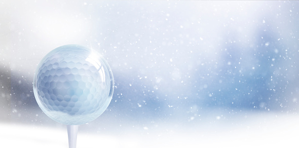 Glass Christmas ball with golf ball against blurred blue background with snowflakes