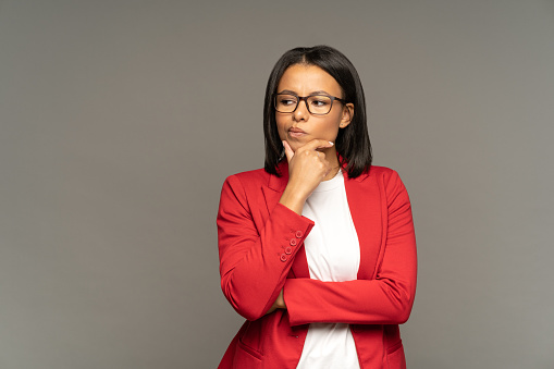 Young businesswoman making important decision doubtful thinking and pondering on problem solution or next step in strategy development. Serious african american female pensive, worried and frustrated
