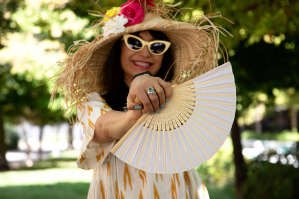 istock smiling woman holding hand fan between fingers 1344796491