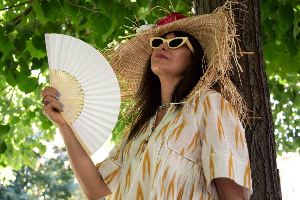 woman fanning herself under a tree