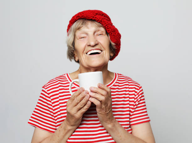 istock old excited lady smiling laughing, holding cup drinking coffee 1344797674