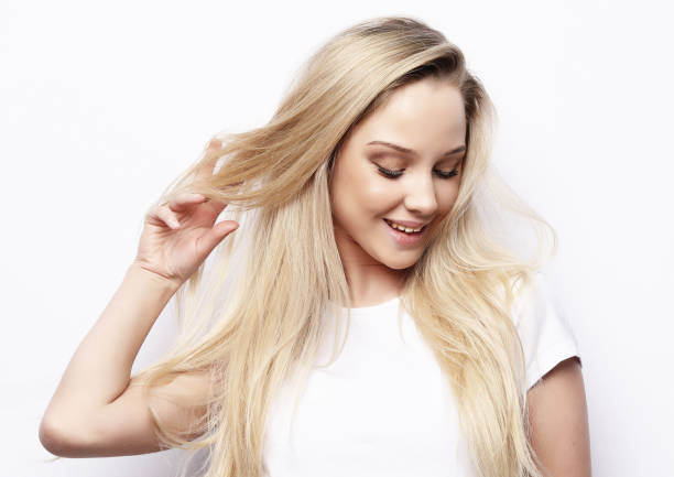 Beautiful happy blond girl touches her hair. Casual clothes. White background.Close up stock photo