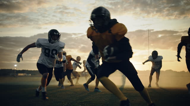 American Football Field Two Teams Compete: Players Pass and Run Attacking to Score Touchdown Points. Professional Athletes Fight for the Ball. Sportsmen Determined to Win Championship. Slow Motion