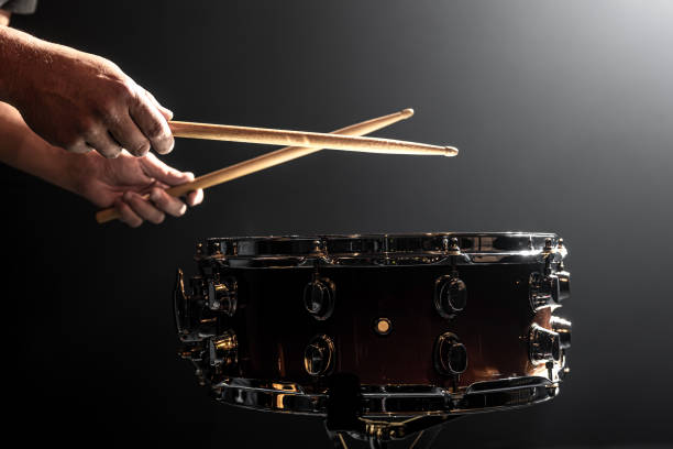istock Snare drum and drummer's hands hitting drumsticks against a dark background. 1344800159