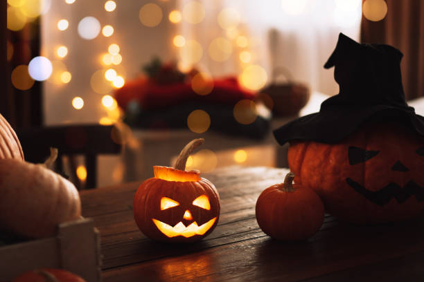 istock Glowing pumpkin with an evil face next to big one in witch's hat 1344800781