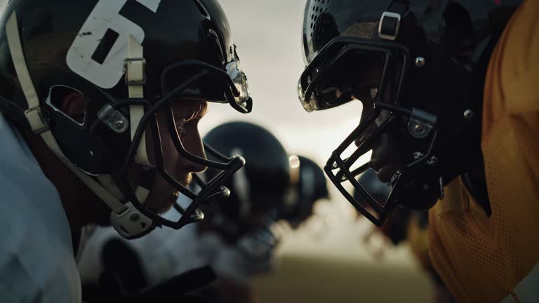 American Football Game Start Teams Ready: Close-up Portrait of Two Professional Players, Aggressive Face-off. Competitive Warriors Full of Brutal Energy, Power, Skill. Dramatic Stare. Cinematic Shot