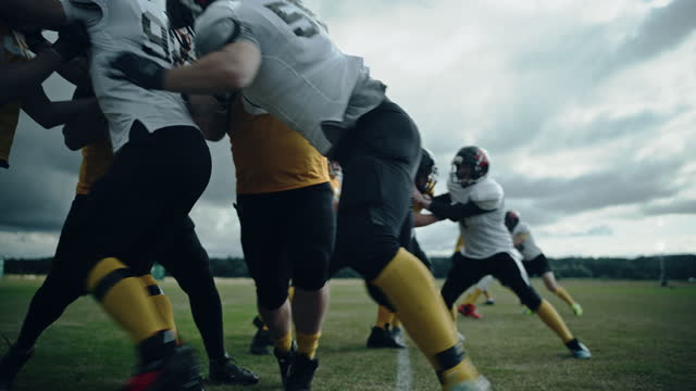 American Football Teams Start Game: Professional Players, Aggressive Face-off, Tackle, Pass, Fight for Ball and Score. Competition Full of Brutal Energy, Power, Skill. Cinematic Handheld Shot
