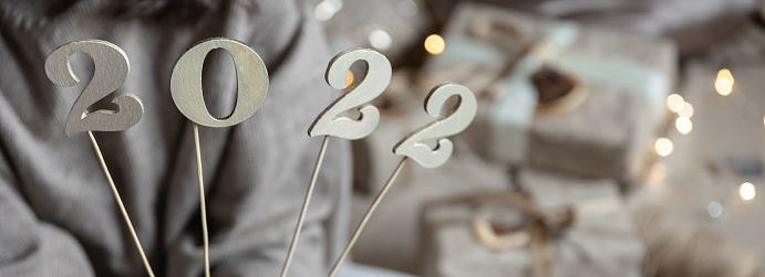 Close-up of decorative numbers 2022 in female hands on blurred background.