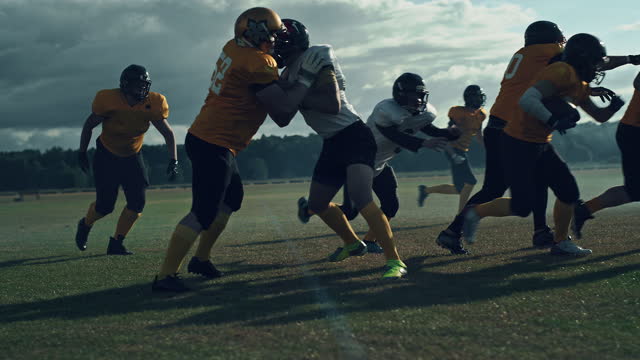 American Football Field Two Teams Compete: Players Pass and Run Attacking to Score Touchdown Points. Professional Athletes Compete for the Ball, Tackle, Fight for Victory. Cinematic Slow Motion