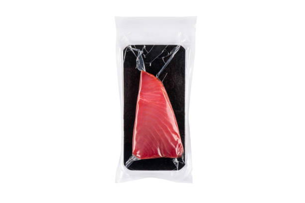 Yellow fin tuna steak in a plastic vacuum bag isolated on a white background. Vacuum packaged seafood. Fresh rare tuna meat steak close up stock photo