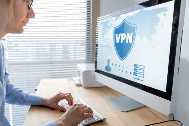 Photo of VPN secure connection for telecommuter. Person using Virtual Private Network technology on computer to create encrypted tunnel to remote server on internet to protect data privacy, home office.