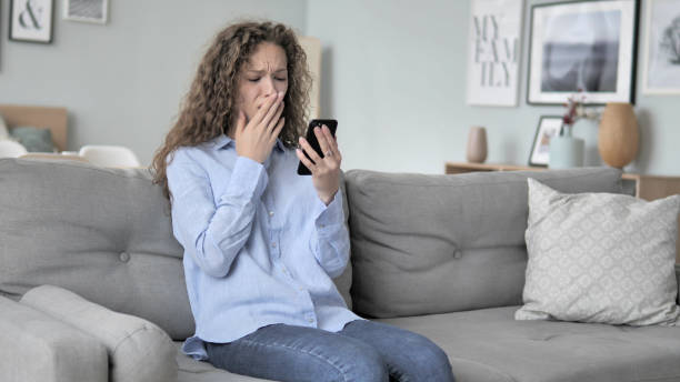 istock Curly Hair Woman in Shock by Loss while Using Phone 1344810332