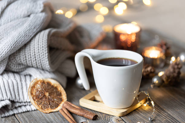 istock Cup of tea on a blurred background with candles, knitted sweaters, and bokeh. 1344811195