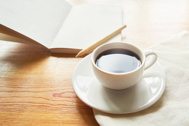 istock Hot coffee on a white cup on linen fabric, notebook in the background. Work at home concept. 1344811445
