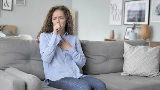 istock Sick Young Curly Hair Woman Coughing while Sitting on Couch 1344811904