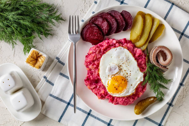 крупным планом лабскаус, солонина, картофельное пюре со свеклой, увенчанной яичницами, нарезанная свекла, с солеными огурцами и ролл-мопсам - rollmops стоковые фото и изображения