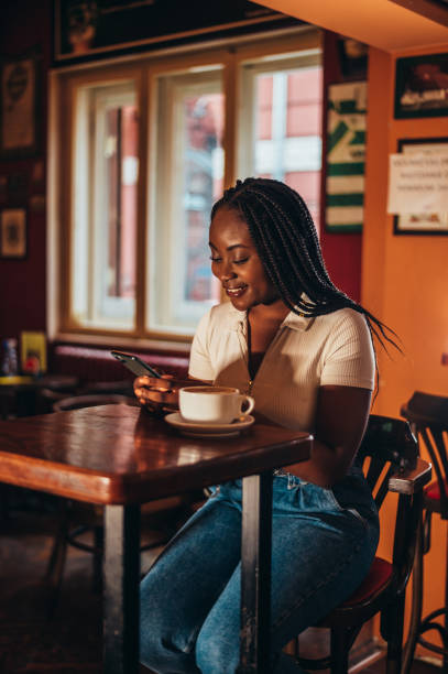 istock African american woman using a smartphone and drinking coffee in a cafe 1344814896