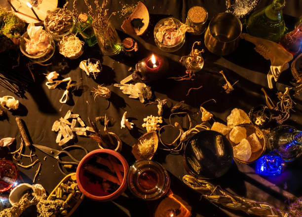 istock Occult and esoteric witch doctor still life. Halloween background with magic objects. Black candles, skull, crystal stones, and potions vials on witch table. Mystic witchery background with weeds. 1344817757