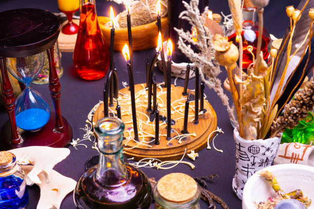 istock Witchcraft still life with black burning candles selective focus. Esoteric gothic and occult witch table for Halloween. Various magic objects and ritual arrangement. Gothic Halloween. 1344817994