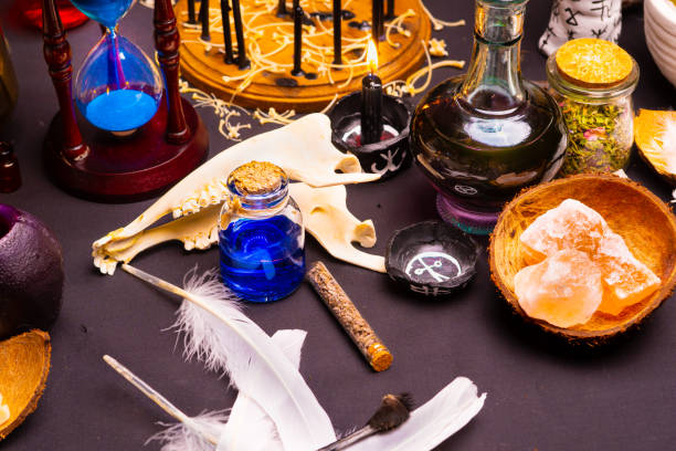 Witchcraft still life with black burning candles selective focus. Esoteric gothic and occult witch table for Halloween. Various magic objects and ritual arrangement. Gothic Halloween.