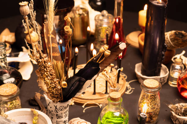 Witchcraft still life with black burning candles selective focus. Esoteric gothic and occult witch table for Halloween. Various magic objects and ritual arrangement. Gothic Halloween.
