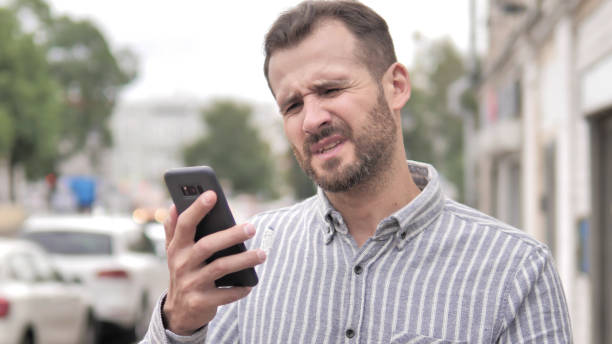 istock Outdoor Beard Casual Man Upset by Loss while Using Smartphone 1344819393