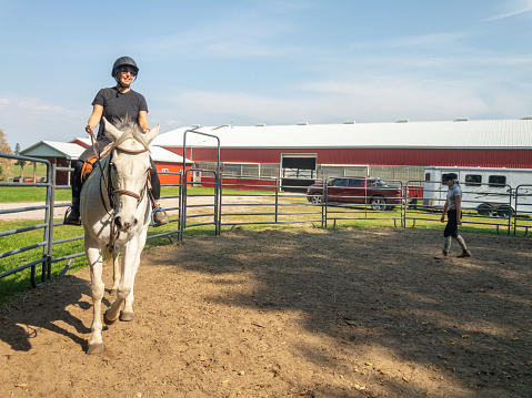 Mujer madura montando a caballo en el paddock photo