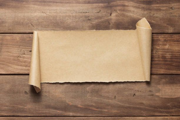 istock curved or scrolled paper at wooden background texture 1344821703