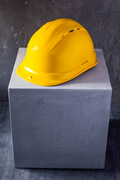 istock Helmet or hardhat on concrete cube or cement block background texture. Construction concept 1344826004