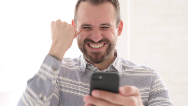 istock Excited Man Cheering Success on Smartphone 1344827125
