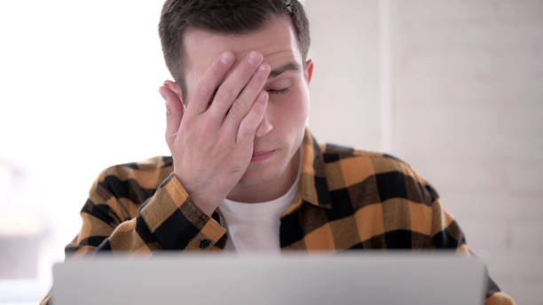 istock Close Up of Young Man with Headache Working on Laptop 1344827940