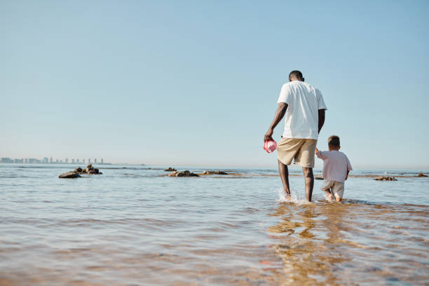 padre e hijo caminando en el agua vista trasera - foto natural fotos fotografías e imágenes de stock