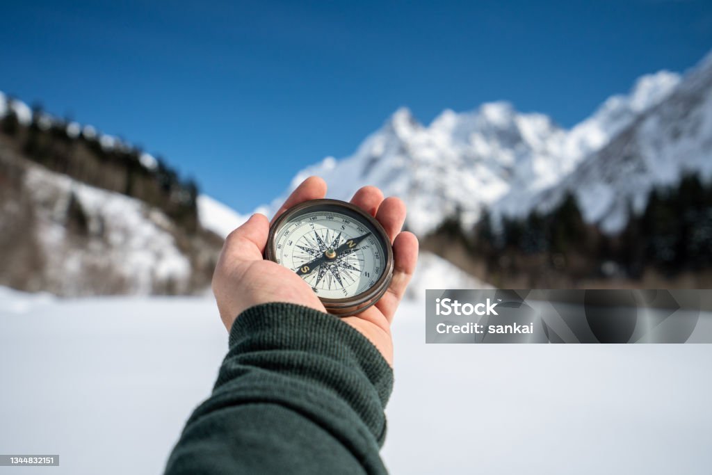 Searching the way Searching the way. Man in the mountains holding vintage compass in a hand. Navigational Compass Stock Photo