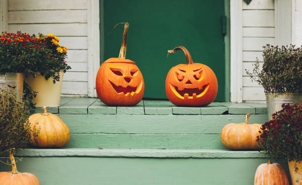 House with halloween orange pumpkin decoration, jack o lanterns with spooky faces on porch Staircase autumn decor. House entrance with halloween pumpkin decoration on wooden stairs, two jack o lanterns with spooky faces on porch of apartment building during all hallows eve porch stock pictures, royalty-free photos & images