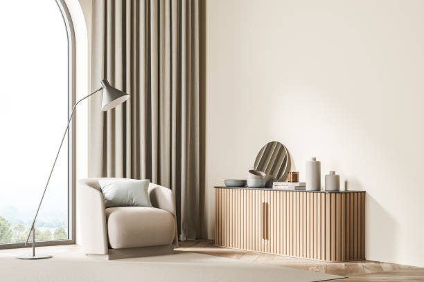 istock Light beige waiting room corner with arch window, sideboard, armchair and lamp 1344835954