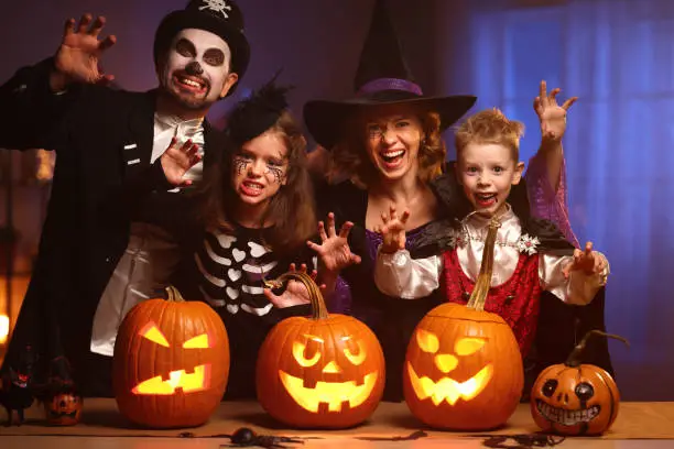 Photo of Young family mother father and children in Halloween costumes celebrating all hallows eve at home