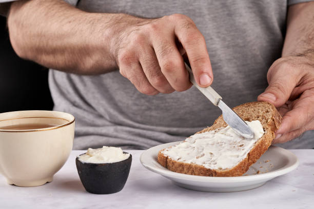 istock man's hands smearing cream cheese on slice of bran bread for breakfast 1344840358