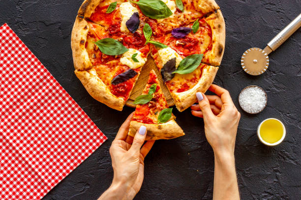 istock Female hands hold slice of pizza. Overhead view 1344844683