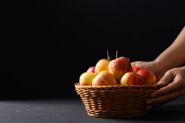 istock Red apple fruit in a basket on black background with hand, Still Life 1344846707