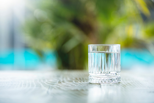 Clean water in small glass on table. Healthy concept. Outdoor bright shoot