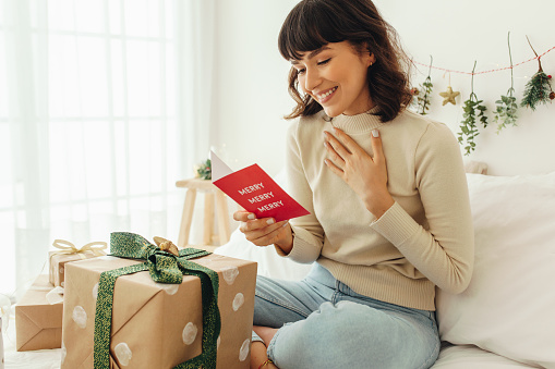 Mujer feliz leyendo una tarjeta de felicitación navideña photo