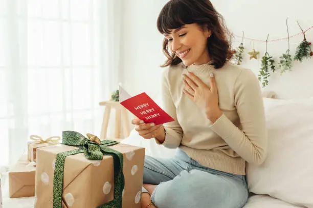 Photo of Happy woman reading a christmas greeting card